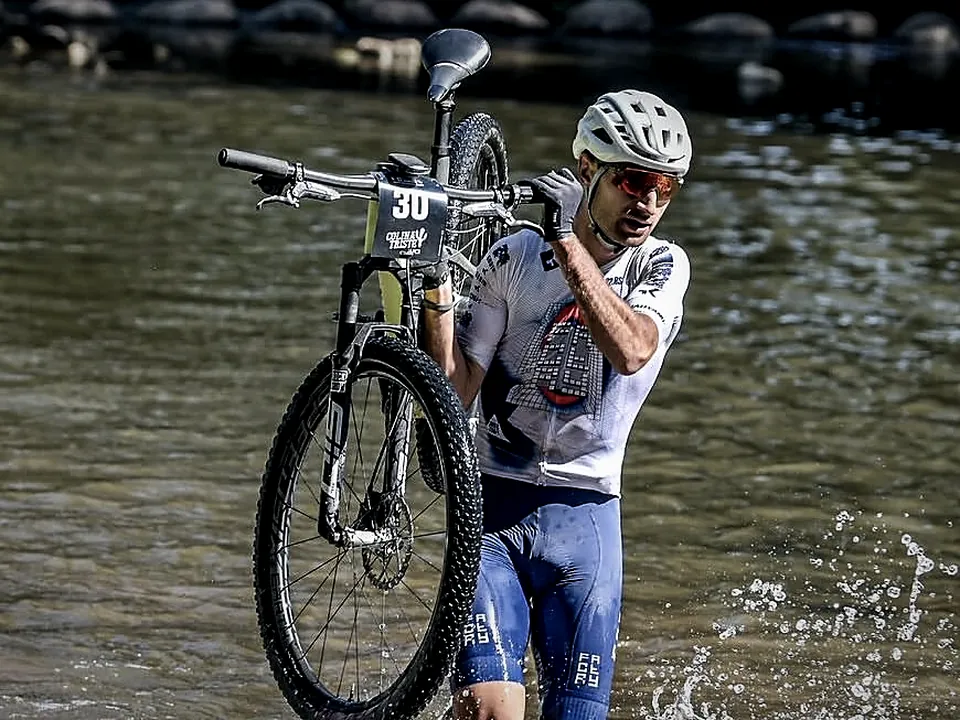 Alex Sempere, nutricionista deportivo de AGÓN Entrenamiento Ibi, cruzando un río con su bicicleta de montaña en una carrera